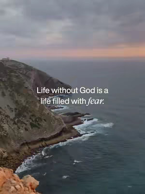 An aerial view of a rocky coastline at dusk. A cliff hugs the left side of the frame, while the sea stretches into the distance with a cloudy sky. The text overlayed on top reads Life without God is a life filled with fear, in a white, sans-serif font.