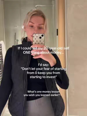 A selfie-style video cover image. A woman with blonde hair is holding a phone in front of a mirror. Text overlays are present, conveying advice and asking a question related to personal finance and money lessons. The background has a bathroom setting.
