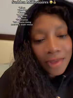 A person in a black hoodie looks towards the camera. Text overlayed on part of the screen includes the phrase "Sudden Millionaires" as well as a list of zodiac signs and other astrological terms. The image is framed from the chest up, with their face filling most of the frame