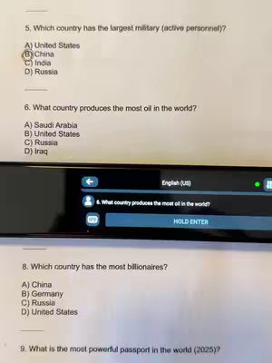 The image shows a close up of a smartpen and a screen displaying multiple choice questions.