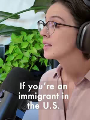 A medium shot shows a woman from the side, wearing glasses and headphones, speaking in front of a microphone. Lush green plants are visible in the background. Text overlay reads, 'If you're an immigrant in the U.S.'