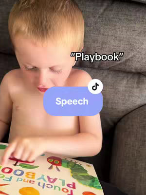 A young child is seated on a gray couch, gazing down at a colorful book in his hands. A text overlay states 'Playbook' at the top, and below that, a light-blue rounded rectangle with the word 'Speech' in white text is displayed. The child appears shirtless, focusing intently on the book.