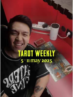 The cover image features a man smiling in front of a red background. The text 'TAROT WEEKLY' and the date range '5 - 11 may 2025' are overlayed on the image. In the background is a red wall with a power strip, a white device, and other objects.