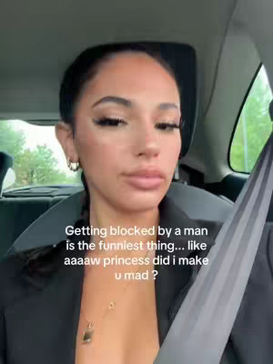 A woman in a car takes a selfie, looking at the camera. Text overlays the image. The woman has dark hair, is wearing earrings and a low neckline, and has a serious expression. The background shows a car interior and blurred outdoor scenery.