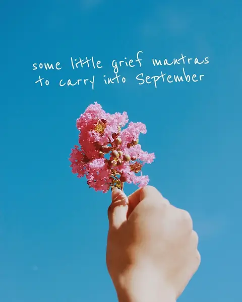 A hand holding a cluster of pink flowers against a clear blue sky and hook text on the top part of the frame.