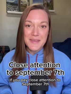 A woman with brown hair is centered in the frame against a neutral background. She wears a light blue hoodie with a red and white stripe detail on the hood. Text is overlaid, with a bold headline in a larger, more prominent font, with some additional text below it. She is speaking into a black microphone held at the bottom of the frame.