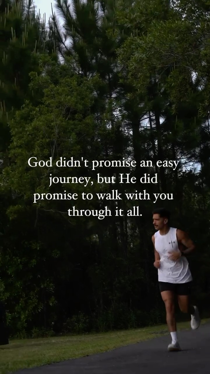 A shot featuring a man running on a paved path, with text overlaid. The background shows thick green foliage and trees, creating a natural setting. The man is wearing a white sleeveless shirt, black shorts, and white shoes. Text in a white font is layered on top of the natural landscape, containing an inspirational quote.