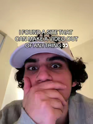 A young man with dark hair and a white baseball cap with black text stares wide-eyed at the camera, with his hand covering his mouth in apparent surprise. The background is a light-colored wall.