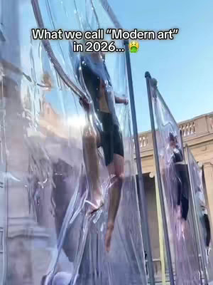 The cover image shows an outdoor installation of what appears to be humanoid figures encased in large transparent plastic structures. The figures are positioned within the structures, with the background consisting of buildings and a clear blue sky. Text overlay on the image states, "What we call ''Modern art'' in 2026..." along with a green, nauseated-face emoji.