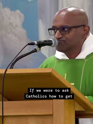 A man wearing glasses and a priest's collar speaks behind a wooden podium with a microphone. The background is a blurred interior with what appears to be cloudy shapes.