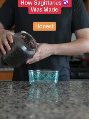 A person in a black shirt pouring dark beans from a clear jar into a patterned bowl on a countertop. Text overlays are present.