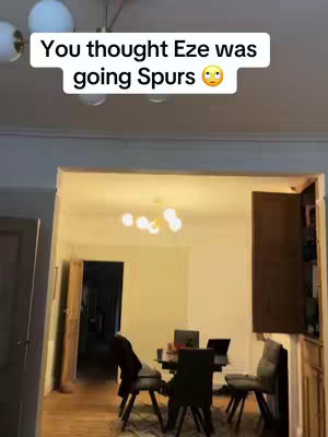 The image shows a room interior with a table and chairs, and a text overlay. The room has a ceiling with a light fixture, and the text overlay is at the top center. The text overlay reads: You thought Eze was going Spurs with an emoji of a face.