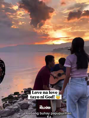 A group of young people plays music on a beach at sunset. The sky is filled with orange and purple hues, and the water reflects the colors. Text overlays are visible on the image