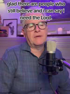 The image captures a man in a blue shirt, wearing glasses and speaking into a microphone. Text overlays the image with a religious message.