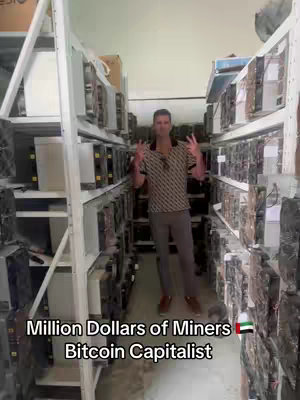 The cover image features a man standing in front of rows of server racks, in a data center filled with Bitcoin miners. Overlay text reads "Million Dollars of Miners Bitcoin Capitalist". The composition is vertical, with the man as the central figure, wearing a patterned shirt and light-colored pants, giving a peace sign with both hands. The lighting seems uniform, emphasizing the rows of machinery.