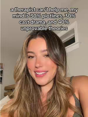 A woman smiles into the camera, which is a close-up shot. Overlay text at the top is a light color and the background is a room.