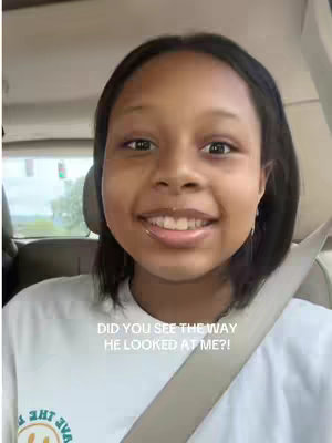 A young woman with dark hair and a white shirt is smiling at the camera. She is sitting in the front seat of a car, with a seatbelt across her chest, and the car's interior is visible in the background. Text overlays the image.