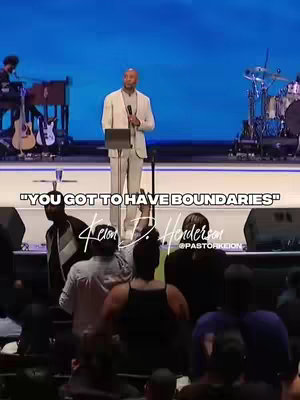 The image shows a man speaking into a microphone on a stage with a large audience. Above him, text reads, "YOU GOT TO HAVE BOUNDARIES." The stage has a blue backdrop, and musical instruments are visible on either side.