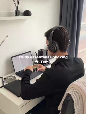 A person sits at a desk with a laptop, holding a cup. The scene is lit with natural light from a window, and text overlays are present at the bottom. Accessories for studying are on the desk, and the person is wearing headphones.