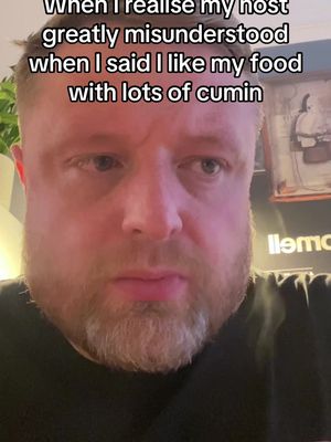 A close-up shot of a man with fair skin, a short beard, and short reddish hair. He has a slightly distressed expression, with furrowed eyebrows and a downturned mouth. The background is softly blurred but appears to be an interior setting with warm lighting and hints of decor.