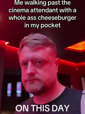 A selfie-style shot of a man in a cinema setting, with red lighting. The man, who has a beard, is centered in the frame, looking at the camera with a serious expression. Text overlays detail the content's nature.
