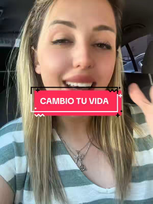 A woman in a car smiles at the camera with a red banner overlaid with text. She has long blonde hair and is wearing a white and green striped shirt with a silver necklace. The background suggests a vehicle interior, perhaps a car.