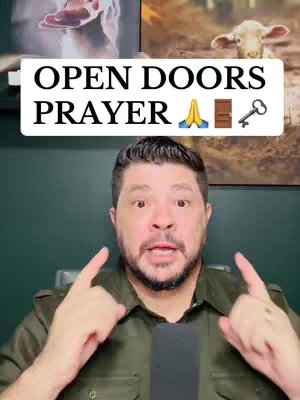 The cover image features a man looking directly at the camera with a surprised expression. Above his head is a white rectangle with the text "OPEN DOORS PRAYER" in black, along with emojis of praying hands, a door, and a key. The man has a neutral skin tone, short brown hair, and a short beard. He is wearing a dark button-down shirt. The background includes pictures and a dark green wall.