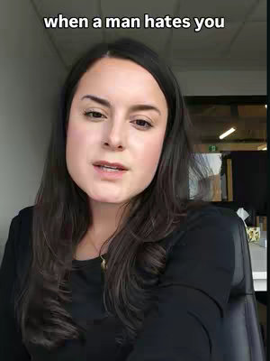 A woman with dark hair and a black top is centered in the frame. The text overlay says 'when a man hates you'. The background suggests an office or indoor setting.