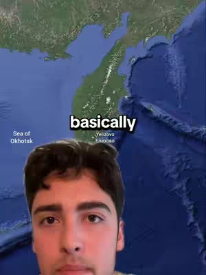 A selfie-style video cover image, featuring a young man in front of a map of a Russian territory. The map is in shades of green and blue, likely representing land and water. The words "basically" appear as a text overlay. The man is looking towards the camera.