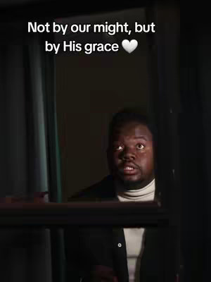A man with a surprised expression is framed in a window. Text overlays read, "Not by our might, but by His grace" with a heart icon.
