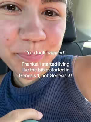 A close-up selfie of a person, presented from the chest up. The person is in what appears to be the front seat of a car. The background is muted, with focus on the subject's face and shoulders. The subject, who is female, has light skin, brown eyes, and brown hair. She is wearing a dark blue tank top with a bright color bra strap. Above the person are texts such as "You look happier!"; below them are the texts "Thanks! I started living like the bible started in Genesis 1, not Genesis 3!"