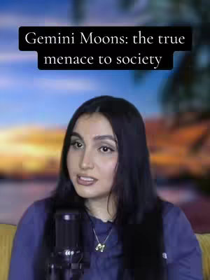 A woman with dark hair, wearing a blue shirt, is in front of a microphone. A black banner with white text overlays the upper section of the image, in front of a blurred sunset background. The woman is looking towards the camera.