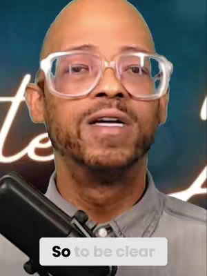 A man with a shaved head and clear-framed glasses is centered in the frame, looking upwards with a slight, open-mouthed expression. A microphone is held in the lower-left corner. The words 'So to be clear' are on a white box in the center-bottom.