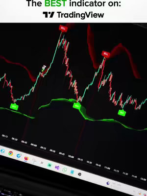 A laptop screen displaying a TradingView chart with technical indicators. The chart shows a stock price trend with red and green candlesticks, and technical indicators overlayed on the chart. The background is dark, and the laptop is partially visible in the foreground.
