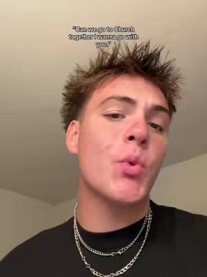 A young man with short, spiky brown hair and a black shirt is the central focus. He has a slightly open mouth and appears to be speaking or making a playful expression. Around his neck are two silver chain necklaces. Above him is the text overlayed over the picture.