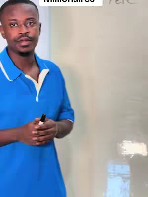 A man in a blue polo shirt stands in front of a white board, holding a black marker. The composition is a medium shot, with a focus on the man's upper body.