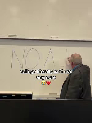 A video cover image from a classroom setting. A man, presumably a professor, is at the board. On the upper half of the whiteboard, someone has written 'NO A!', and the professor is adding the letter 'I' to the end of the word. Below this, a text overlay reads 'college literally isn't real anymore' accompanied by a yellow face and a broken heart emoji.