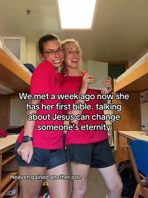 Two young women, smiling, stand close together in a dorm room. One woman wears glasses and is on the left, while the other holds a bible. Text overlays highlight their meeting, the bible, and how talking of Jesus can change eternity.