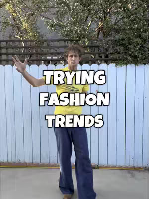 A man stands outside in front of a white fence, with arms outstretched. Overlaid on the image is the text "TRYING FASHION TRENDS."
