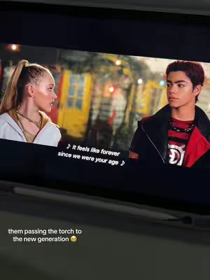 A screenshot from a movie scene with two people on a bright background, with text overlayed at the bottom of it .