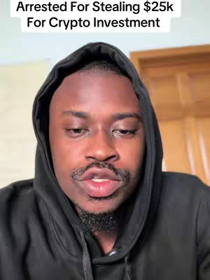 A close-up shot of a Black man in a black hoodie. Above him, in the video frame, is the title text "Arrested For Stealing $25k For Crypto Investment" in a white, sans-serif font. He has short, dark hair, a trimmed mustache and goatee. The background is out of focus, featuring a cream-colored wall and door frame.