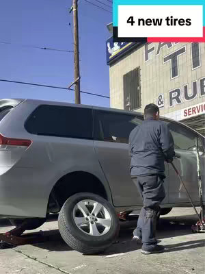 A silver minivan is parked on a paved surface, with one tire removed. A man, likely the creator, stands near the car, facing away from the camera. Above, a text overlay states "4 new tires". The setting appears to be outside a tire shop.