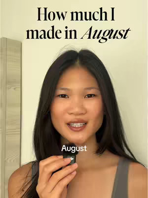 A woman with long dark hair, wearing a gray top, is smiling while holding a small black microphone. Text overlays the image in the top part. The background is a plain light wall.