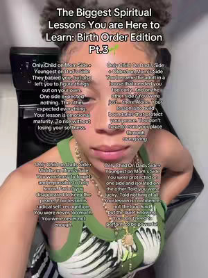 A selfie-style portrait featuring a young woman with her upper body visible. She has curly hair, held up in a bun, and is wearing a stylish sleeveless top. The background is blurred, suggesting an indoor setting with a dark-colored stovetop clearly visible behind her. Text overlays with a white font are placed around the frame. The woman has a neutral expression and is looking towards the viewer.