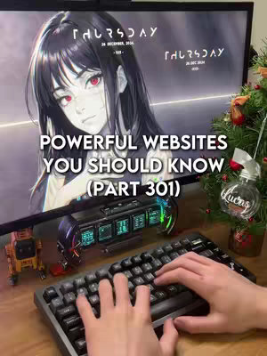 The cover image shows a desktop setup. A computer monitor displays an anime-style illustration of a woman with dark hair and red eyes, with text overlays. Below the monitor is a keyboard with the creator's hands typing. To the right is a small Christmas tree. An orange toy truck and a futuristic-looking object are in front of the monitor.