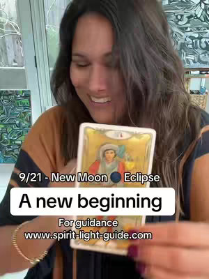 A woman smiles while holding a tarot card, overlaid with text about a new moon eclipse and a website address.