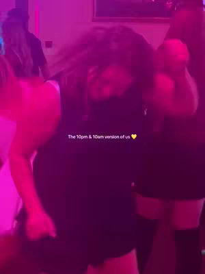 A blurry image of two people in a brightly lit room, possibly a club setting. The lighting is predominantly pink and purple, giving a vibrant atmosphere. The subjects are partially visible, suggesting they are dancing or in motion, with long hair visible.
