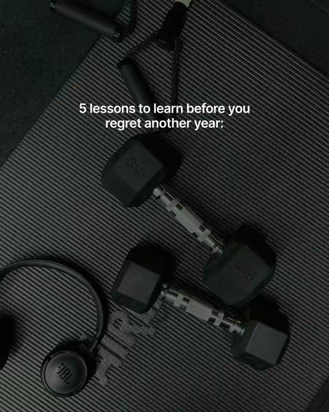An angled shot atop a dark, textured surface, likely a workout mat.  Two black dumbbells with silver handles and black weights are positioned in the center.  A pair of black headphones with a JBL logo are in the bottom left corner, next to what appears to be a jump rope. The image has a muted, grayscale color palette.