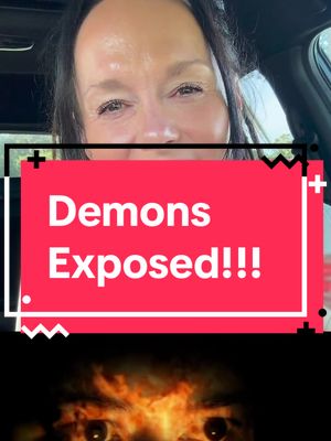 The cover image is composed of three distinct sections. At the top, a smiling woman is shown from the chest up, likely indoors, with natural lighting. She's positioned slightly off-center, and the background is softly blurred. Below her, a bright red rectangular banner dominates the middle, containing the words "Demons Exposed!!!" in large, white, bold text, which is centered and vertically stacked. The banner is outlined in a series of black plus signs and zigzags. At the bottom, an image of blazing eyes dominates the bottom of the image.