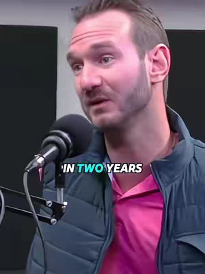 A man in a blue jacket and a pink shirt is speaking into a microphone. Overlayed text, in large white font, reads "IN TWO YEARS".